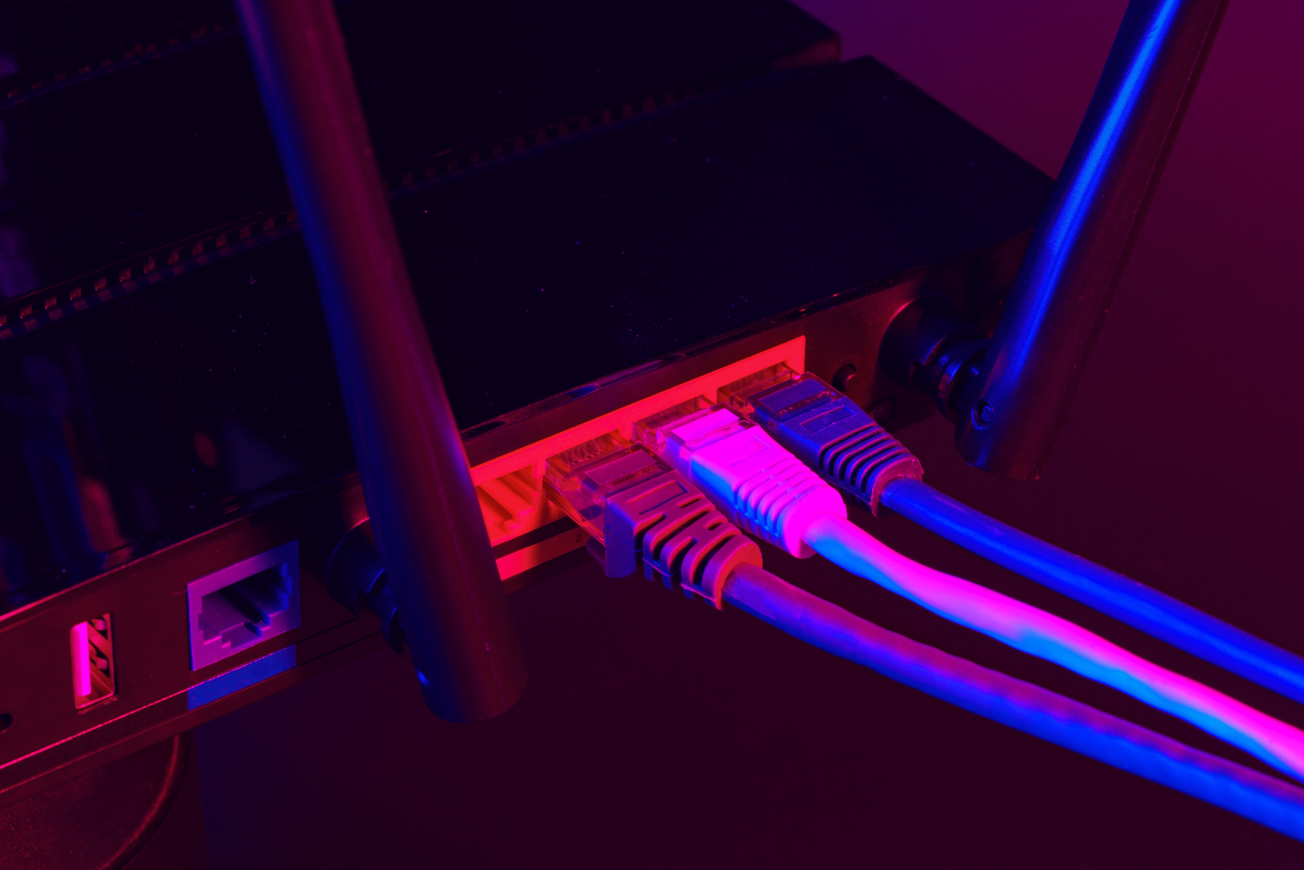 Cables plugged in a Wi-Fi router on dark background close up